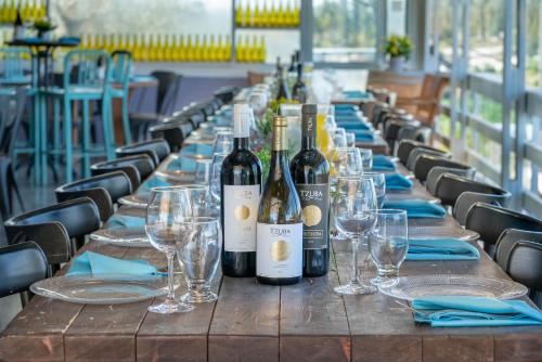 a long table with wine bottles and glasses on it at Tzuba Hotel in Ẕova