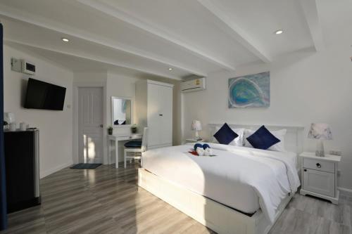 a white bedroom with a large white bed and a desk at Kata White Villas in Kata Beach