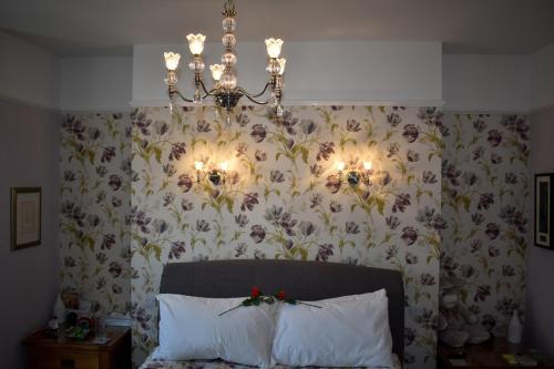 TLC Exmouth Bed and Breakfast في اكسماوث: غرفة نوم بها ثريا وورق جدران زجاجي