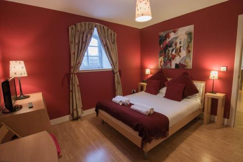 a bedroom with a bed with red walls and a window at 241 Fabulous three bedroom apartment on the second floor with parking in Edinburgh