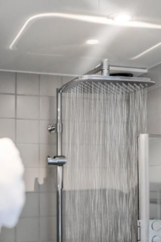 a shower with a shower curtain in a bathroom at Hotell Furusund in Furusund