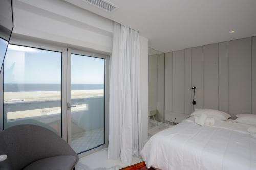 a bedroom with a white bed and a large window at Sea Side Luxury Apartment in Figueira da Foz
