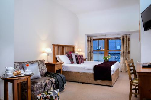 a bedroom with a bed and a chair and a window at Coachmans Townhouse Hotel in Kenmare