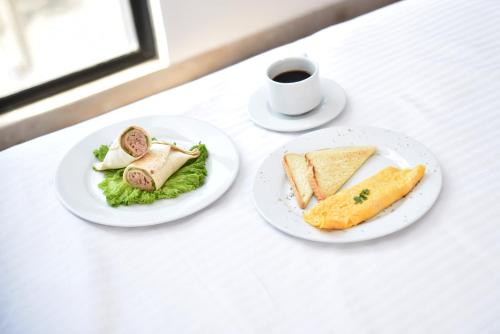 two plates of food on a table with a cup of coffee at Hotel Mio Boutique in Cúcuta