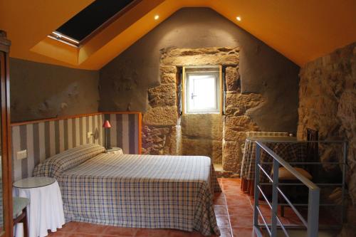 um quarto com uma cama num quarto de pedra em Rectoral de Prado em Piñeiro
