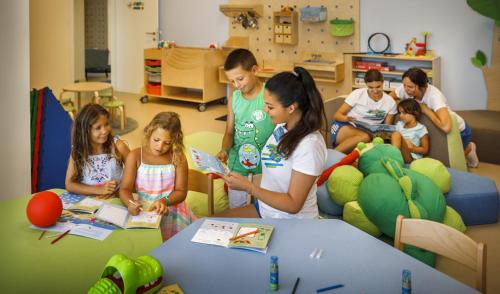 a group of children reading books in a classroom at Valamar Camping Padova in Rab