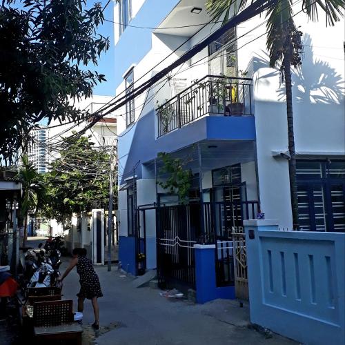 a woman standing in front of a blue and white building at Sena home 4th-Rooftop Overlooking Danang Dragon bridge in Da Nang