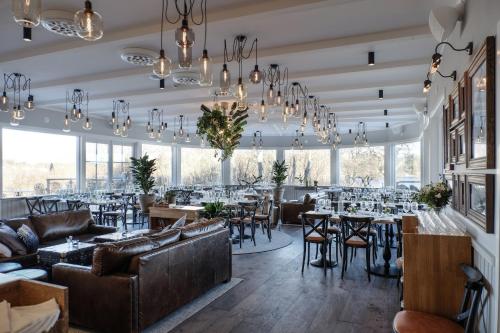 a restaurant with tables and chairs and chandeliers at Hotell Furusund in Furusund