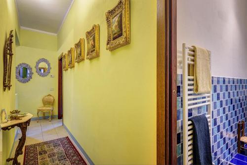a bathroom with a yellow wall with pictures on the wall at Garden House in Montepulciano