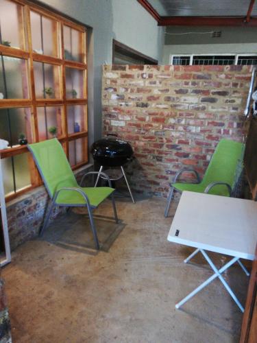 a room with two green chairs and a brick wall at Pillow Place Parys in Parys