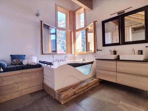 een grote badkamer met een bad en een raam bij VAUJANYLOCATIONS - Chalet Opaline in Vaujany