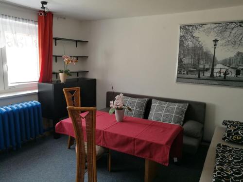 uma sala de estar com uma mesa com uma toalha de mesa vermelha em A+R Pension em Plzeň