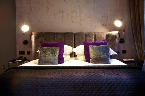 a bedroom with a large bed with purple pillows at Malmaison London in London