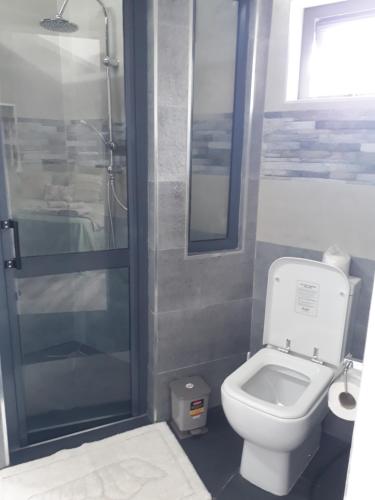 a bathroom with a toilet and a glass shower at Hello Guest House in Quatre Bornes
