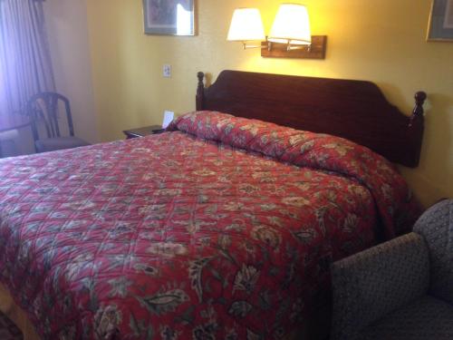 a bed in a hotel room with a red bedspread at Stardust Motel in Naperville