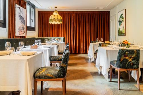 a restaurant with white tables and chairs and a chandelier at CoolRooms Palacio de Atocha in Madrid