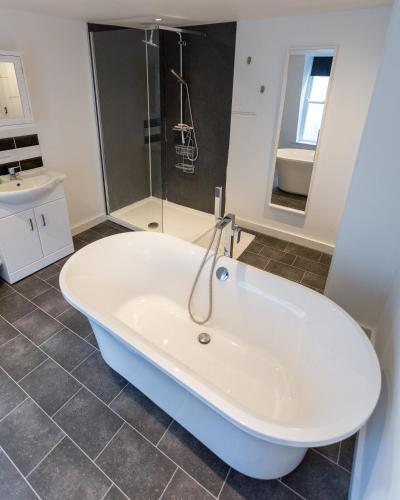 a white bath tub in a bathroom with a shower at Ocean Apartment, 50 yds to Beach, Sleeps 10 in Weymouth