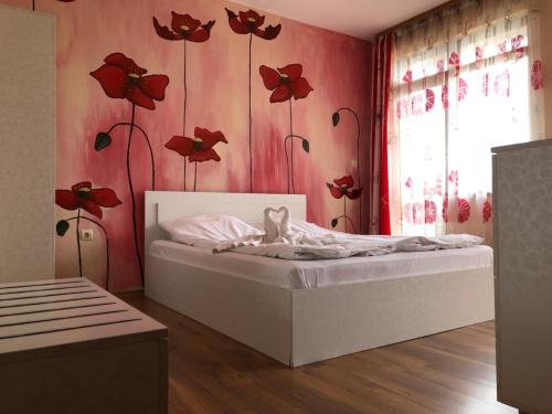 a bedroom with a bed with red flowers on the wall at Guest House Arima in Sushina