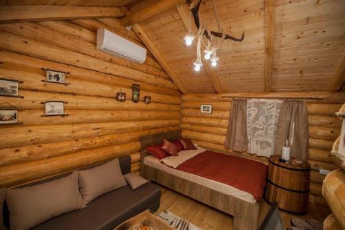 um quarto num chalé de madeira com uma cama e um sofá em Studio - apartmani Brvnare em Trebinje