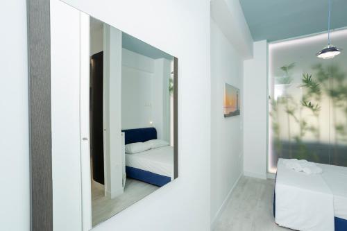 Dormitorio blanco con espejo y cama en AthensBlues Paleo Faliro Center, en Atenas