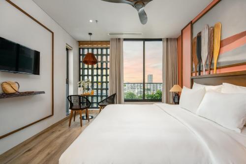 a bedroom with a large white bed and a large window at Seahorse Tropical Da Nang Hotel by Haviland in Da Nang