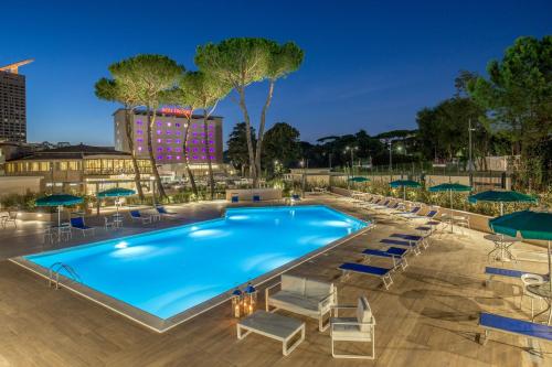 una piscina con sedie a sdraio e ombrelloni di notte di Hotel Cristoforo Colombo a Roma