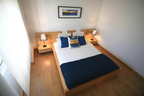 a small bedroom with a bed with blue pillows at D. João I Apartment in Almada