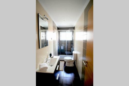 een badkamer met een wastafel, een toilet en een spiegel bij D. João I Apartment in Almada