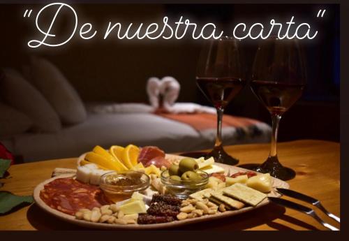 a plate of food on a table with two glasses of wine at Refugio del Maipo Lodge in San José de Maipo
