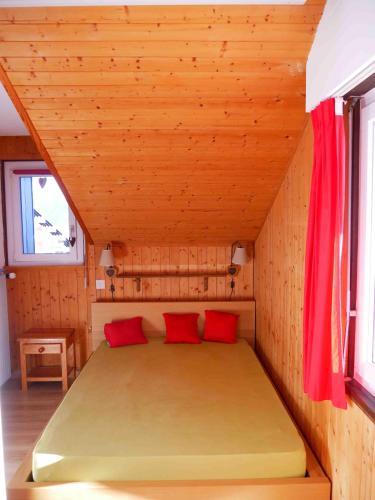 a bed in a wooden room with red pillows at Romantic Chalet-Style Flat with Mountain View in Torgon