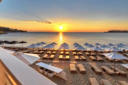 a beach with chairs and umbrellas at sunset at Unique Villa Melia Lagonisi in Kalívia Thorikoú