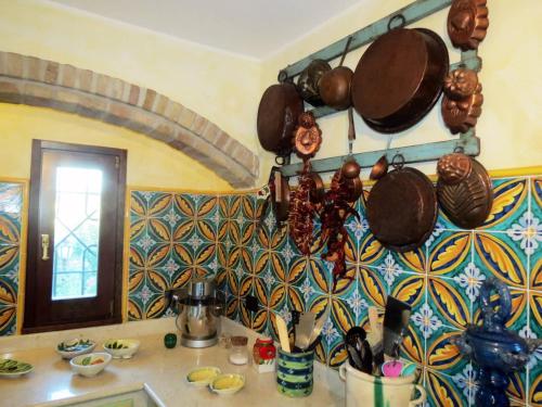 Una cocina con ollas y sartenes colgadas en una pared. en Olivella, en Campagnano di Roma
