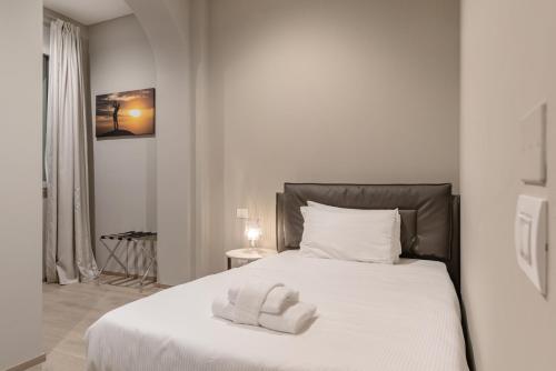 a white bedroom with a bed with two towels on it at JOIVY Treviso Vittoria in Treviso