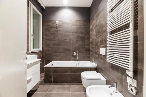 a bathroom with a tub and a toilet and a sink at JOIVY Treviso Vittoria in Treviso