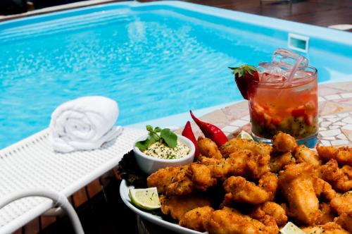 a plate of food on a table next to a swimming pool at Favorita Golden Hotel e Eventos in São José