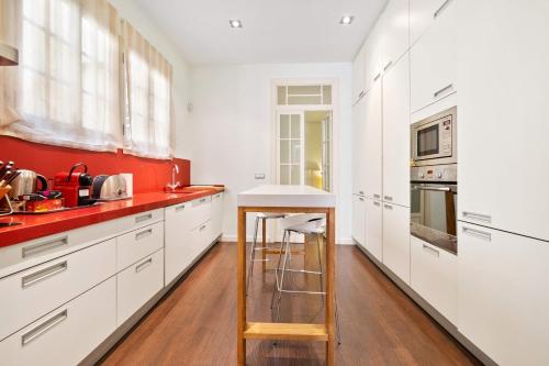 una cocina con armarios blancos y una pared roja en Bennecke Bailen, en Alicante