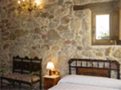 1 dormitorio con cama y pared de piedra en Los Jerónimos en La Tuda