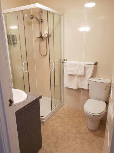a bathroom with a shower and a toilet and a sink at Commercial Hotel in Alness