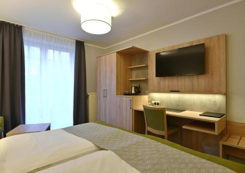 ein Hotelzimmer mit einem Bett, einem Schreibtisch und einem TV in der Unterkunft Hotel Restaurant Waldesruh in Emstek