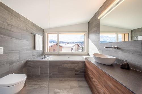 a bathroom with a tub and a toilet and a sink at LAAX Homes - Casa Majo 5,5 in Flims