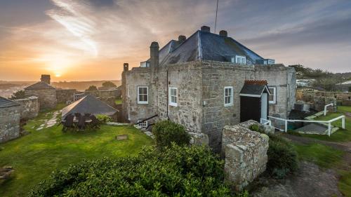 een oud stenen huis met een zonsondergang op de achtergrond bij Star Castle Hotel in Hugh Town