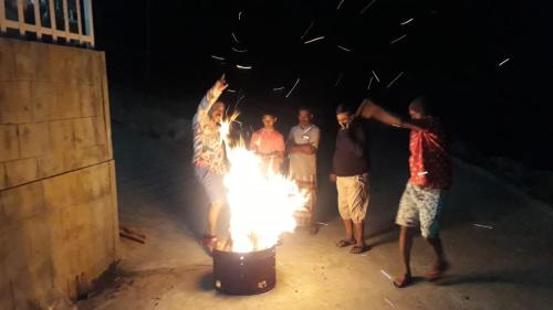 a group of people standing around a pot of fire at Aden Valley Resort in Kanthalloor