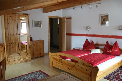 Un dormitorio con una gran cama de madera con almohadas rojas en Haus Hildegard en Neustift im Stubaital