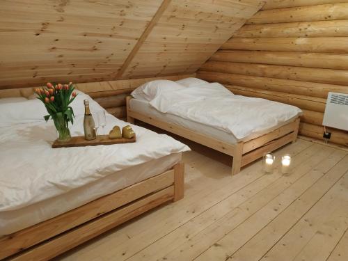 Dos camas en una habitación de madera con flores y una botella de vino en Zalesie - wyjątkowe domki nad jeziorem, en Zalesie