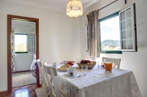 une table de salle à manger avec une nappe blanche dessus dans l'établissement Casas DeCá & DeLá, à Ponte de Lima