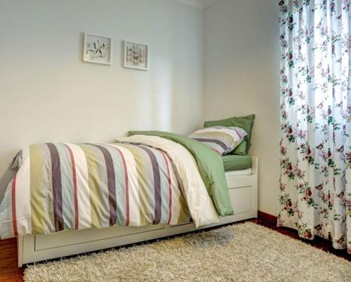 a small bedroom with a bed with a curtain at Casas DeCá & DeLá in Ponte de Lima