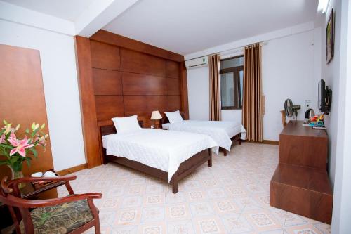a hotel room with two beds and a chair at Viet Huong Hotel in Ninh Binh