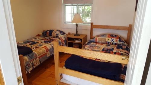 a bedroom with two bunk beds and a lamp at TeelCoveCottageMaine in Saint George