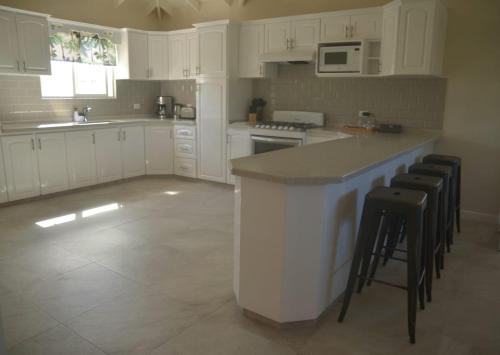 a kitchen with white cabinets and a counter with stools at Ixoras Beach Apartments in Saint Peter