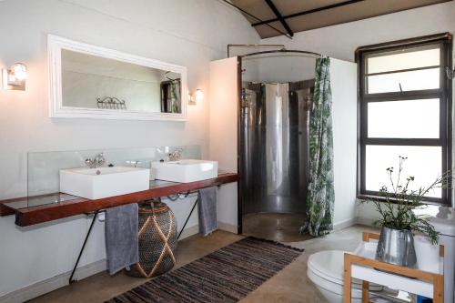 Un baño con dos lavabos y una ducha. en Serondela Lodge, en Mbalastinte